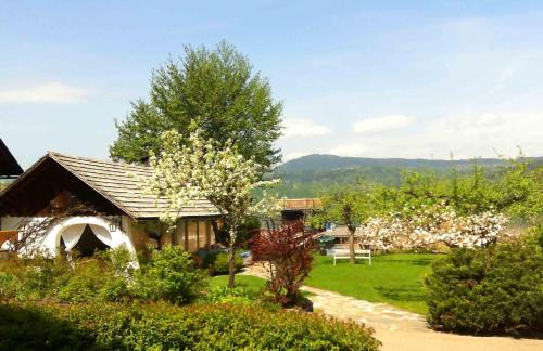 a house with a garden with flowering trees in front of it at Hotel Seehof in Maria Wörth