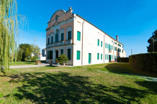 a large white building with green windows on a grass field at Villa da Ponte B&B in Cadoneghe