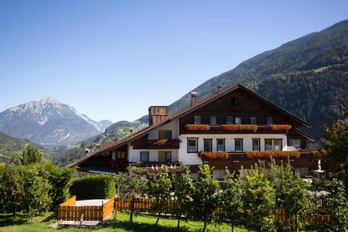 a house with a fence and mountains in the background at Kinderhotel Sailer in Wenns