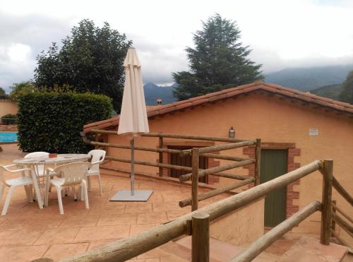 a patio with an umbrella and a table and chairs at Apartamento en pleno Montseny Mas Romeu Turisme Rural in Arbúcies