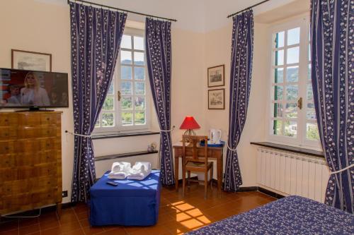 una camera da letto con tende bianche e blu e un tavolo di L' Amandola a Levanto