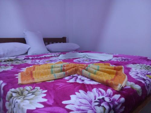 a bed with two blankets and pillows on it at Lavendra Guset House in Adams Peak