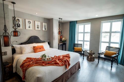 um quarto com uma cama grande e um cobertor laranja. em Sanouva Saigon Hotel em Ho Chi Minh