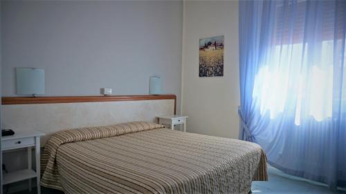 a small bedroom with a bed and a window at Hotel Marta in Forlì