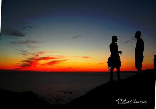 two people standing on the beach watching the sunset at B&B Les Chambres Rooms & Suite in Santa Teresa Gallura