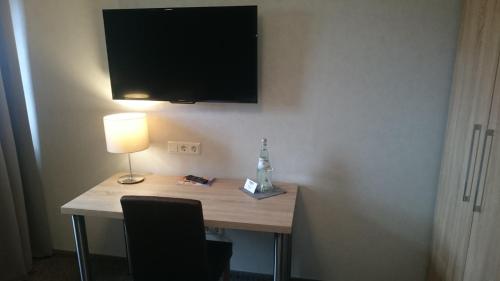 a desk with a lamp and a television on a wall at Seehotel Losheim in Losheim