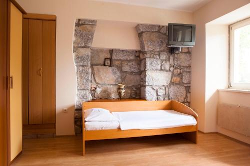 łóżko w pokoju z kamienną ścianą w obiekcie Apartments Delić w mieście Ika