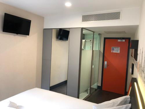 a hotel room with a red door and a mirror at easyHotel Birmingham in Birmingham