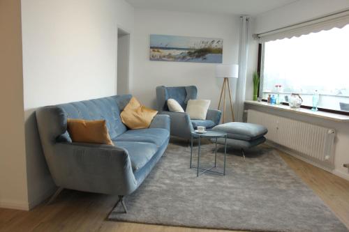 a living room with a blue couch and two chairs at StrandChalet Scharbeutz in Scharbeutz