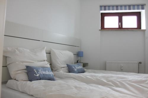 a white bed with two blue pillows on it at StrandChalet Scharbeutz in Scharbeutz
