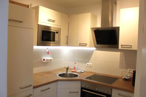 eine kleine Küche mit einer Spüle und einer Mikrowelle in der Unterkunft StrandChalet Scharbeutz in Scharbeutz