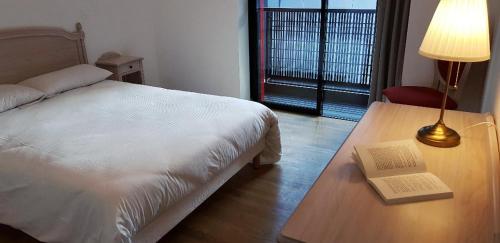 Un dormitorio con una cama y una mesa con un libro. en Médicis Home Strasbourg, en Estrasburgo