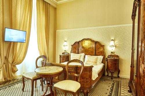 a bedroom with a bed and a table and chairs at Grand Hotel Continental Bucuresti in Bucharest