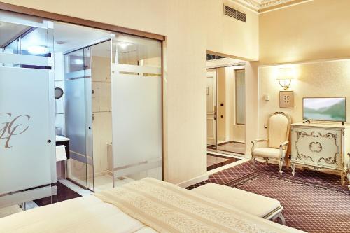 a bedroom with a bed and a chair and a television at Grand Hotel Continental in Bucharest