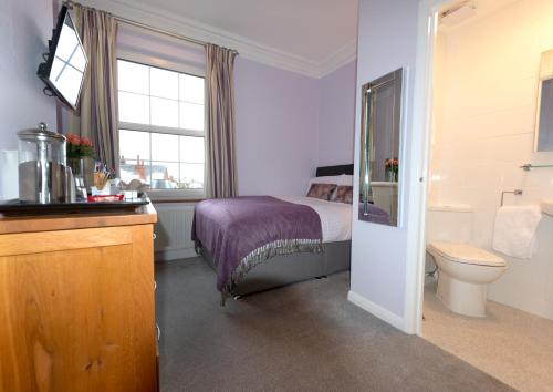 a bedroom with a bed and a toilet and a window at The Pytchley Inn in West Haddon