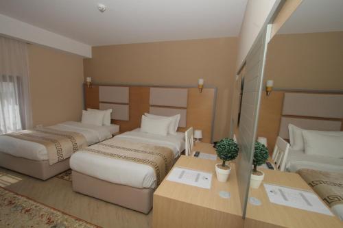 a hotel room with two beds and a table with plants at Capital Tirana Hotel Bruçi in Tirana