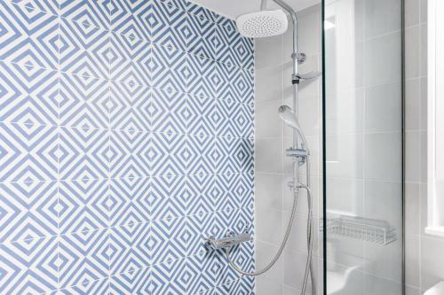 a bathroom with a shower with blue and white tiles at Retropolitan Living Athens in Athens