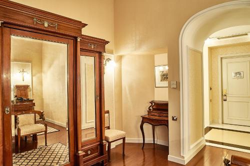 a hallway with a mirror and a chair and a piano at Grand Hotel Continental Bucuresti in Bucharest