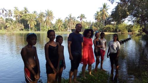 a family poses for a picture in front of the water at Priyanna Guest, Forest view in Polonnaruwa