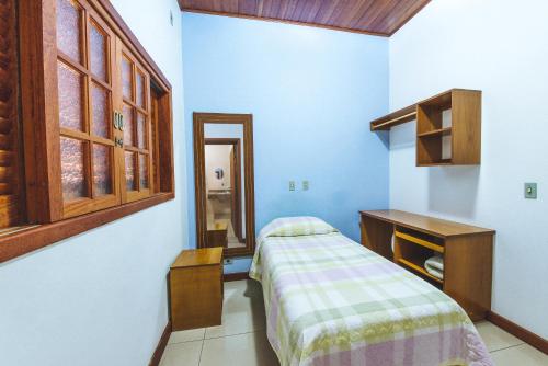 a bedroom with a bed and a desk and a mirror at AM Confort Hotel in Gastão Vidigal