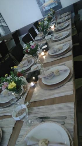 a long table with white plates and flowers on it at Hotel Horto in Rondonópolis