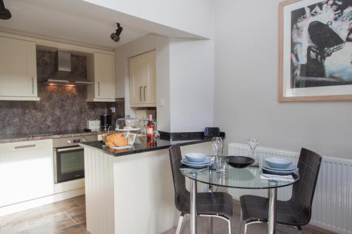 a kitchen with a table with chairs and a counter top at Tethera at Coal Yeat in Spark Bridge
