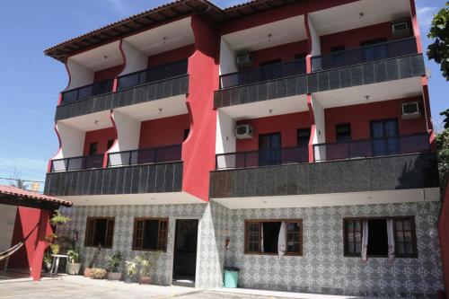 a red and white building with balconies at Pousada da Zezé in Guarapari