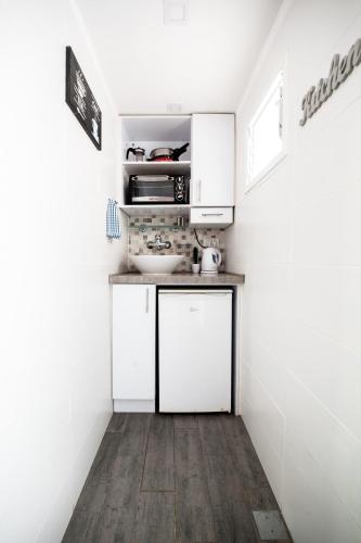 Stunning Studio By The Beach في تل أبيب: مطبخ صغير بخزائن بيضاء ومغسلة