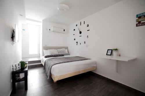 Stunning Studio By The Beach في تل أبيب: غرفة نوم بها سرير وساعة معلقة على الحائط