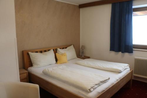 a bedroom with a bed with white sheets and yellow pillows at Pension Singer in Innsbruck