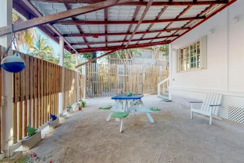 um pátio com uma mesa azul, bancos e uma cerca em Casa DV Suites em Caye Caulker