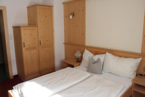 a bedroom with a bed with white sheets and pillows at Pension Singer in Innsbruck