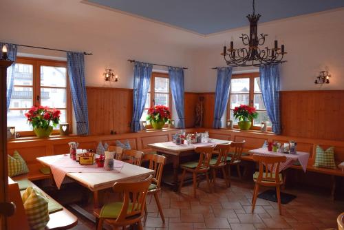 een eetkamer met tafels, stoelen en ramen bij Landgasthaus zum Altwirt Reichersbeuern in Reichersbeuern