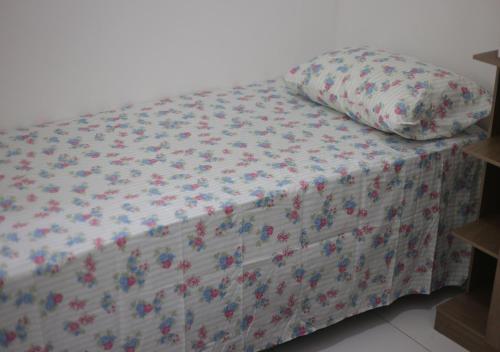 a bed with a floral bedspread and a pillow on it at Residencial Dom Laurindo in Paulo Afonso