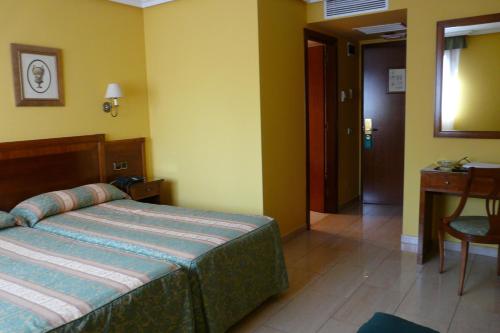a bedroom with a bed and a table and a door at Idh Angel in Oviedo