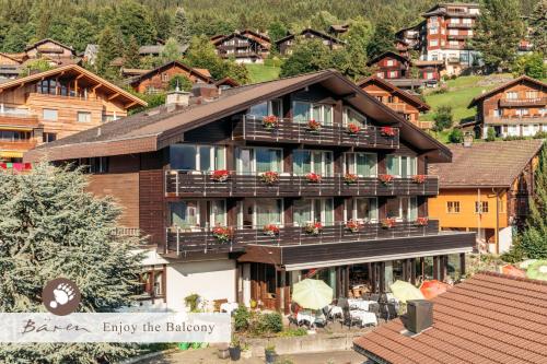 溫根的住宿－Hotel Bären - the Alpine Herb Hotel，一座带阳台的大型建筑,鲜花盛开