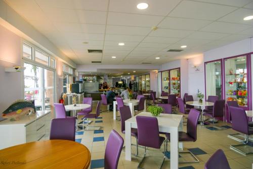 une salle à manger avec des chaises et des tables pourpres dans un restaurant dans l'établissement Association Villa Saint Camille, à Théoule-sur-Mer