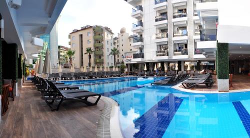 een groot zwembad in een gebouw met stoelen bij Oba Star Hotel - Ultra All Inclusive in Alanya