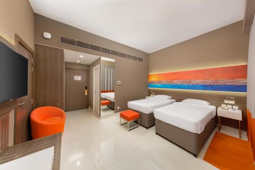a hotel room with two beds and a tv at Citymax Hotel Al Barsha in Dubai