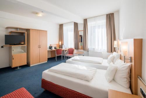 a hotel room with two beds and a desk at Sure Hotel by Best Western Ratingen in Ratingen