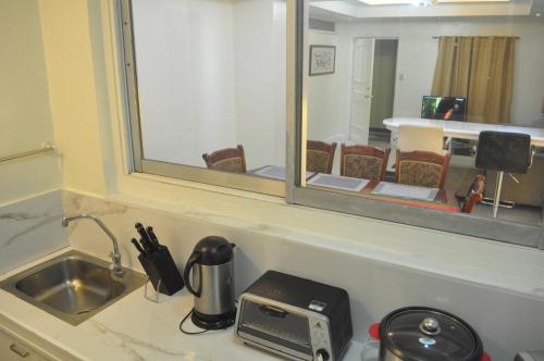 a kitchen counter with a sink and a mirror at Golden Queen Suites in Baguio
