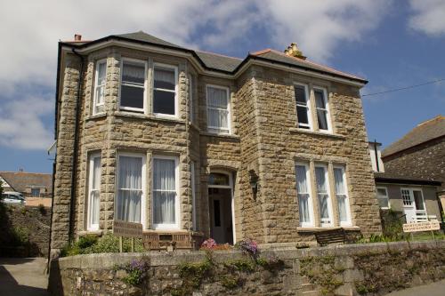 a stone house with white windows on a street at Glenleigh Bed and Breakfast in Marazion