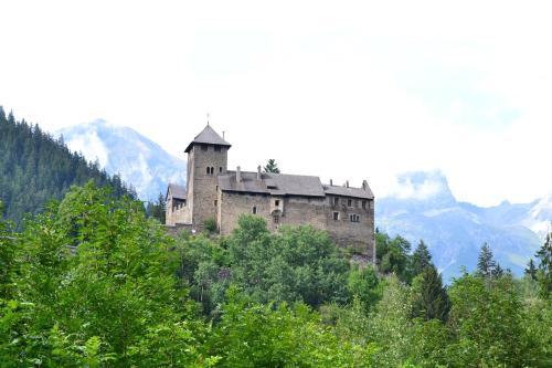 a castle on a hill with mountains in the background at Tobadill Apartments in Tobadill