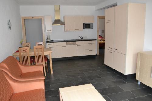 a kitchen with white cabinets and a table and chairs at Tobadill Apartments in Tobadill