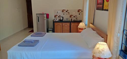 a bedroom with a white bed with blue towels on it at Primavera Holiday Homes-FAMILY RUN GOAN GUEST HOUSE in Candolim
