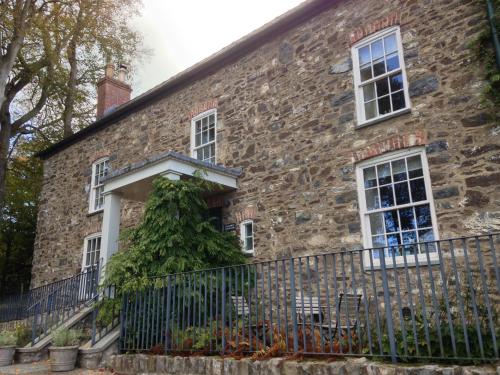an old stone house with a fence at The Farmhouse at Bodnant Welsh Food in Conwy