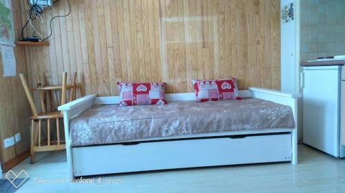コトレにあるSTUDIO COSY AVEC TERRASSE ET JARDINETの赤い枕が備わるドミトリールームのベッド1台分です。