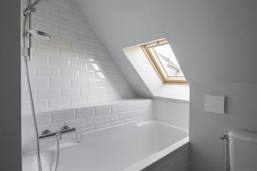 uma casa de banho branca com um chuveiro e uma janela em La Hune by Cocoonr em Saint Malo