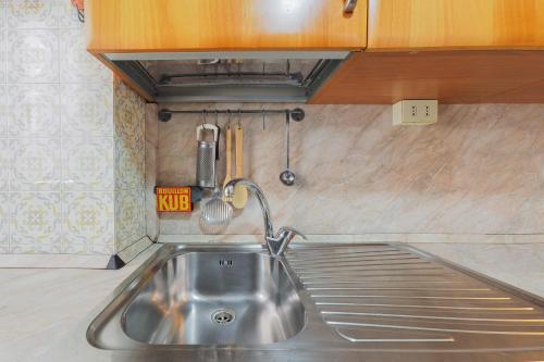 eine Spüle aus Edelstahl in einer Küche mit Holzschränken in der Unterkunft PrimoPiano - Ressi in Mailand