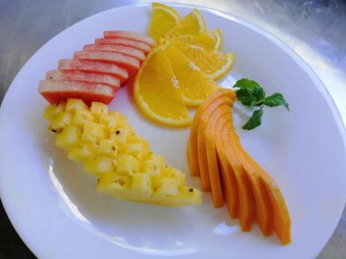a white plate with fruits and vegetables on it at Amaluna Resorts in Negombo